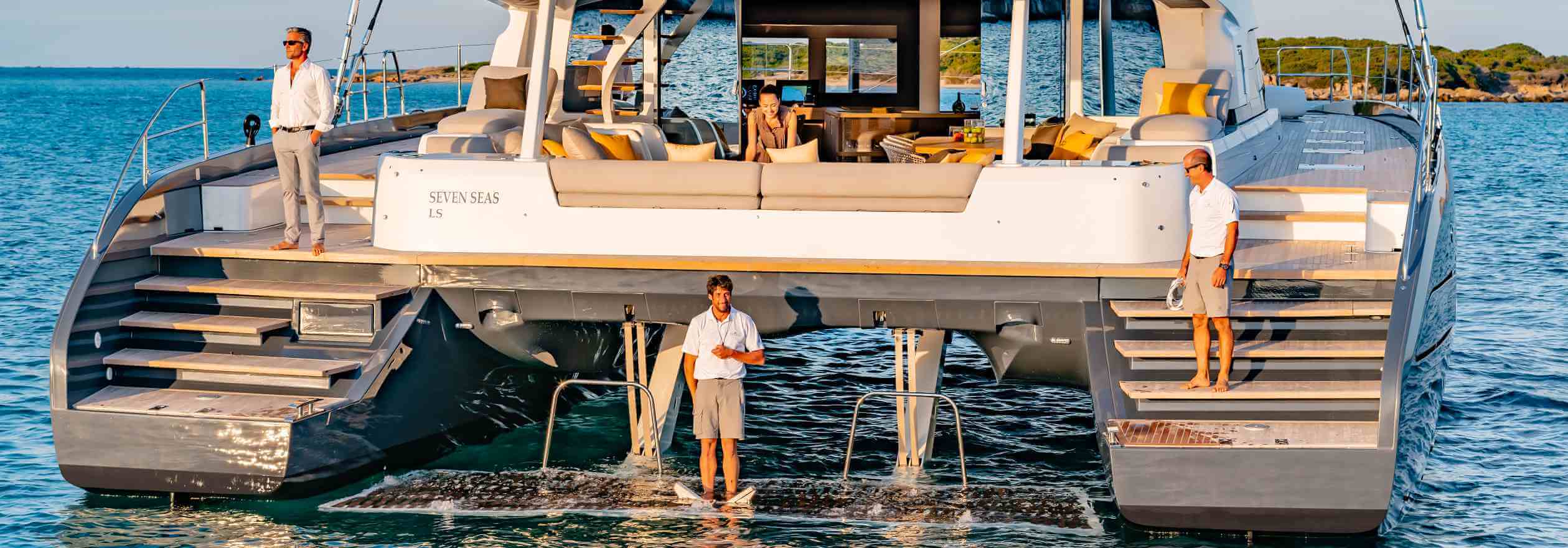 	Foto de la parte trasera de un catamarán marca lagoon con tripulación y pasajeros
